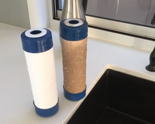 Used dirty water filter next to new replacement filter cartridge for under sink water filter serviced by HC Pure